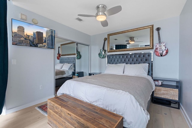 bedroom with visible vents, baseboards, wood finished floors, a closet, and a ceiling fan