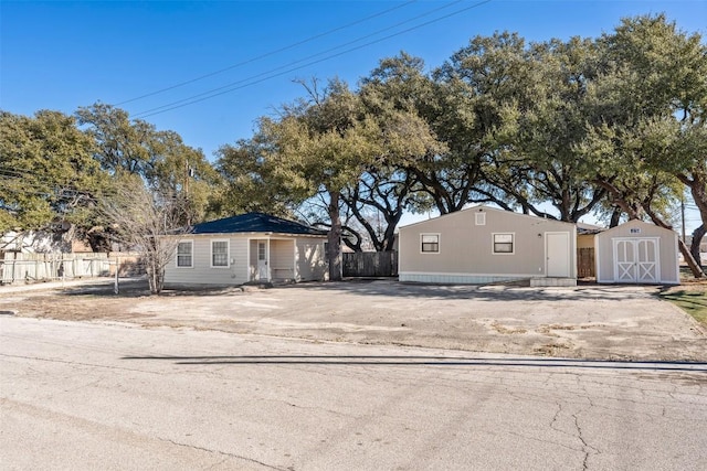 view of front of home featuring an outdoor structure, fence, and a storage shed