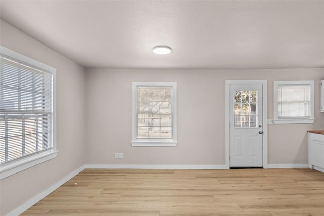 foyer entrance featuring light wood finished floors, a wealth of natural light, and baseboards