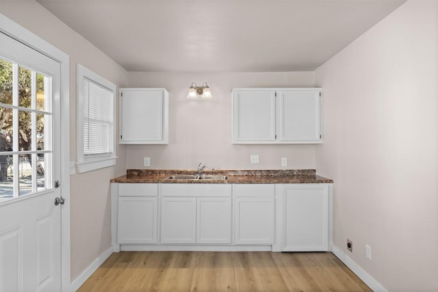 kitchen featuring white cabinetry, a sink, and baseboards