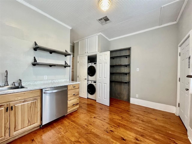 908 W Hopkins St, San Marcos, TX 78666 - kitchen with dishwasher, stacked washer and clothes dryer, a sink, crown molding, and light countertops