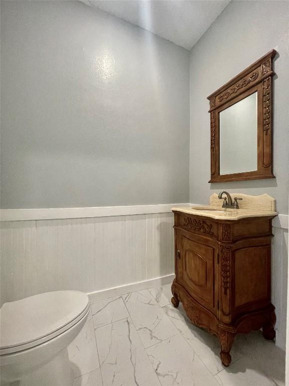 908 W Hopkins St, San Marcos, TX 78666 - half bathroom featuring marble look tiles, wainscoting, toilet, and vanity