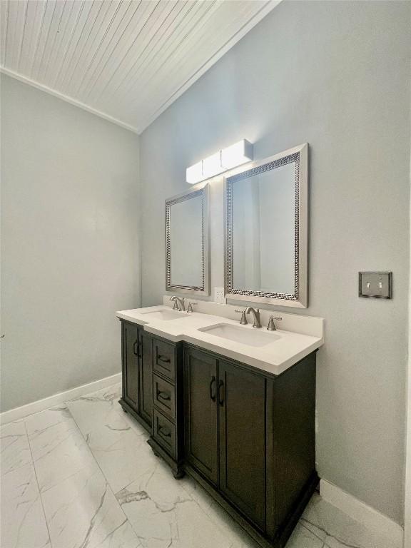 908 W Hopkins St, San Marcos, TX 78666 - bathroom with double vanity, marble look tile flooring, and baseboards