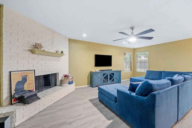 living area with baseboards, a ceiling fan, light wood-style floors, a brick fireplace, and recessed lighting