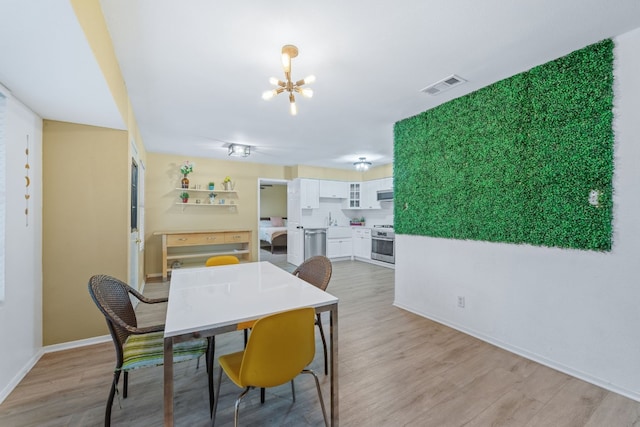 dining space featuring baseboards, light wood-style flooring, visible vents, and a notable chandelier