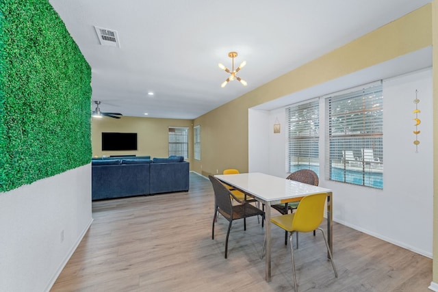 dining space with baseboards, visible vents, wood finished floors, ceiling fan with notable chandelier, and recessed lighting