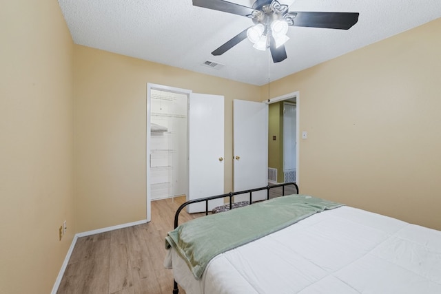 bedroom featuring a textured ceiling, visible vents, baseboards, light wood-style floors, and a closet