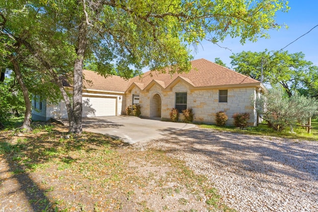 ranch-style house featuring driveway, roof with shingles, and an attached garage