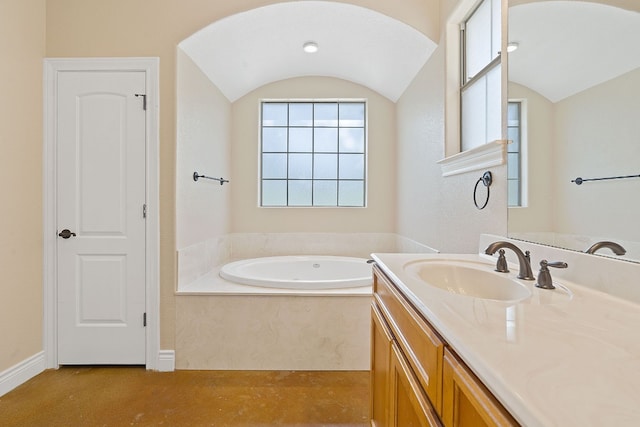 bathroom with a garden tub, vaulted ceiling, concrete flooring, and vanity