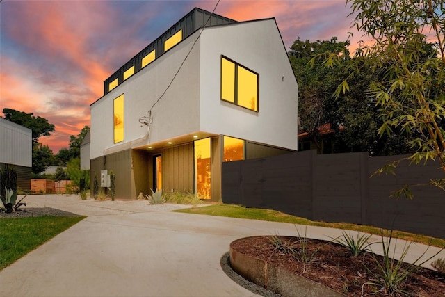 contemporary house featuring concrete driveway, fence, and stucco siding