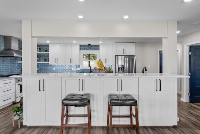 kitchen with white cabinetry, stainless steel fridge, wall chimney range hood, and white electric range oven