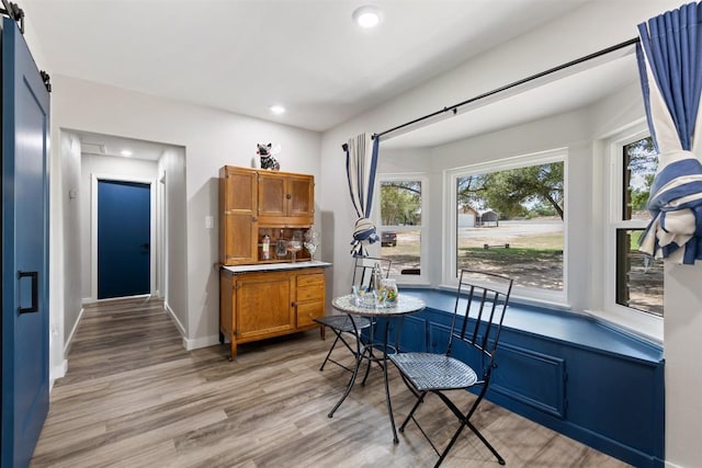 dining space featuring light wood-style floors, recessed lighting, baseboards, and a barn door