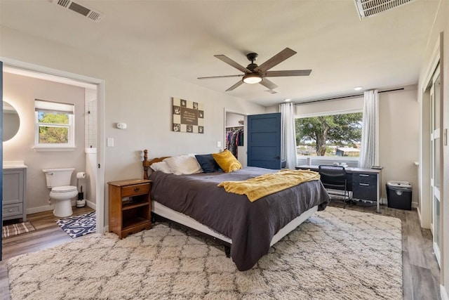 bedroom featuring wood finished floors, visible vents, and connected bathroom