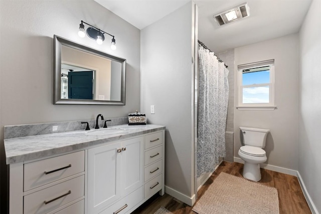 bathroom featuring visible vents, toilet, vanity, wood finished floors, and baseboards