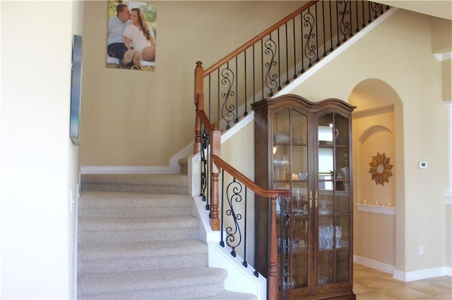 stairway featuring a high ceiling and baseboards