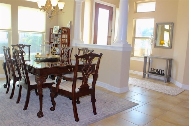 tiled dining space with baseboards, a notable chandelier, and ornate columns