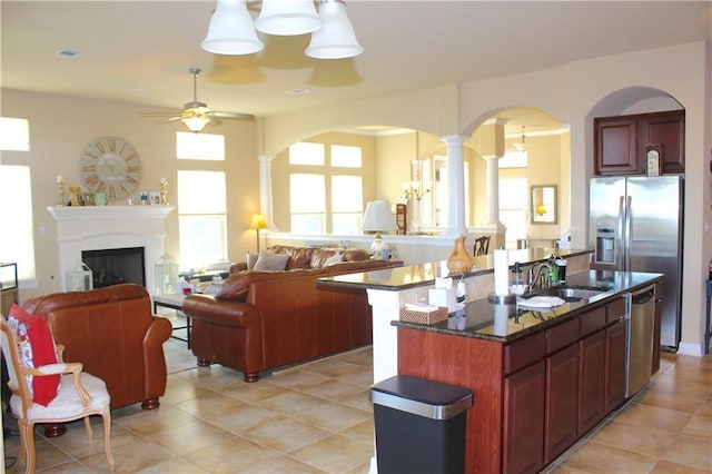 kitchen with a fireplace, appliances with stainless steel finishes, open floor plan, a sink, and an island with sink