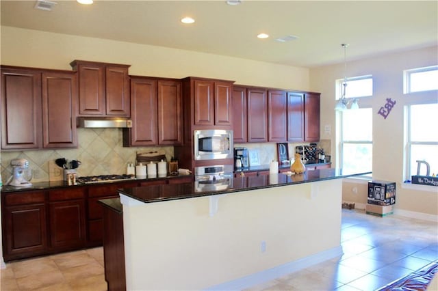 kitchen featuring dark countertops, tasteful backsplash, a kitchen island, and appliances with stainless steel finishes