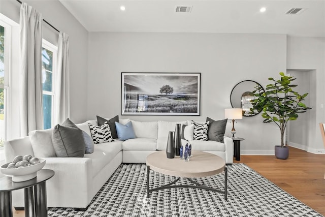 living room featuring baseboards, visible vents, wood finished floors, and recessed lighting