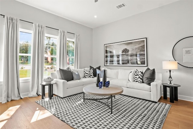 living room featuring light wood-type flooring, baseboards, visible vents, and recessed lighting