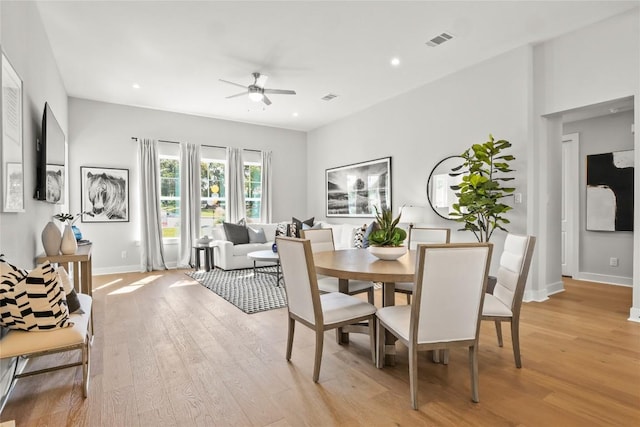 dining space featuring baseboards, visible vents, ceiling fan, and light wood finished floors