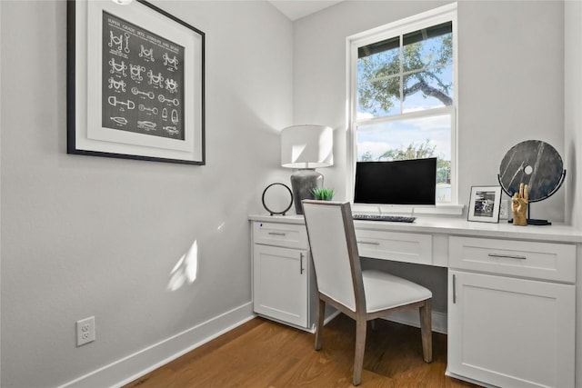 office featuring built in desk, wood finished floors, and baseboards