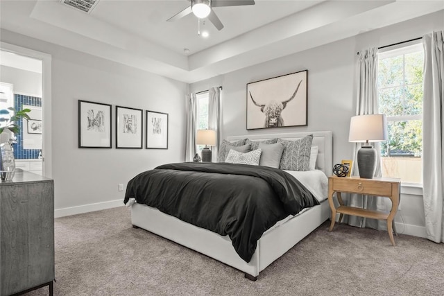 bedroom featuring a raised ceiling, carpet flooring, and multiple windows