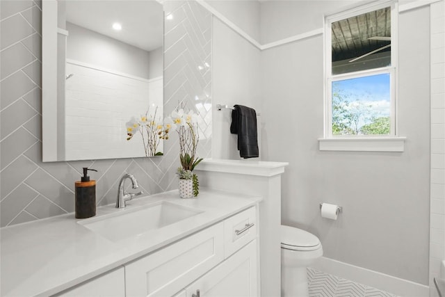 full bathroom featuring toilet, baseboards, decorative backsplash, and vanity