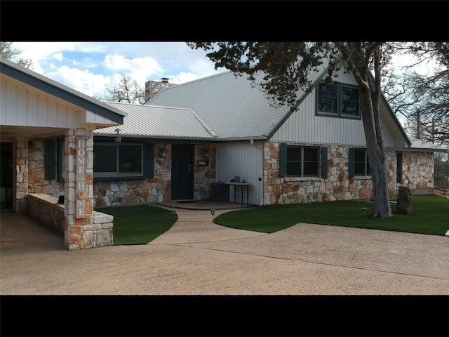 view of front of home featuring metal roof, stone siding, a chimney, and a patio