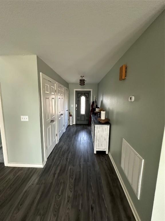 interior space with visible vents, dark wood finished floors, a textured ceiling, and baseboards