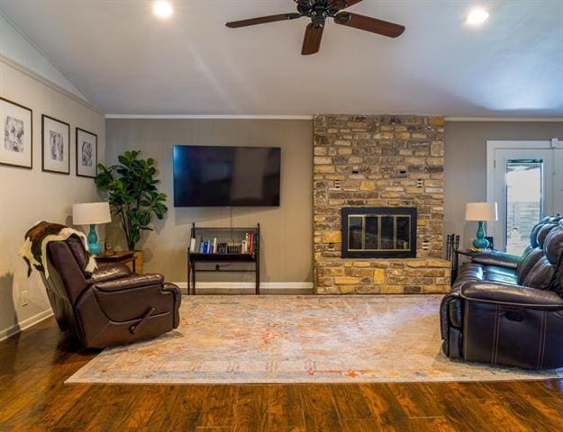 living room featuring a large fireplace, baseboards, ornamental molding, and wood finished floors