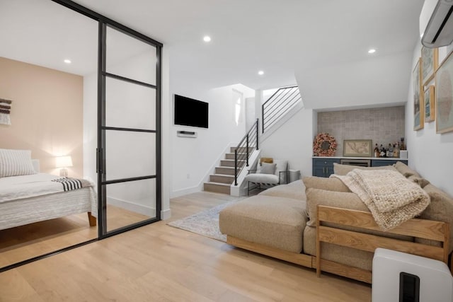 living area featuring baseboards, stairs, an AC wall unit, light wood-type flooring, and recessed lighting