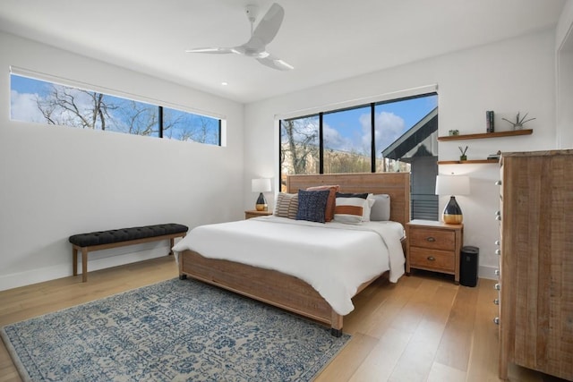 bedroom with light wood-style floors, ceiling fan, and baseboards