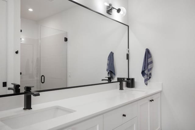 full bath featuring double vanity, a stall shower, a sink, and recessed lighting