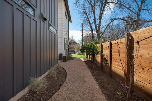 view of side of home featuring board and batten siding and fence