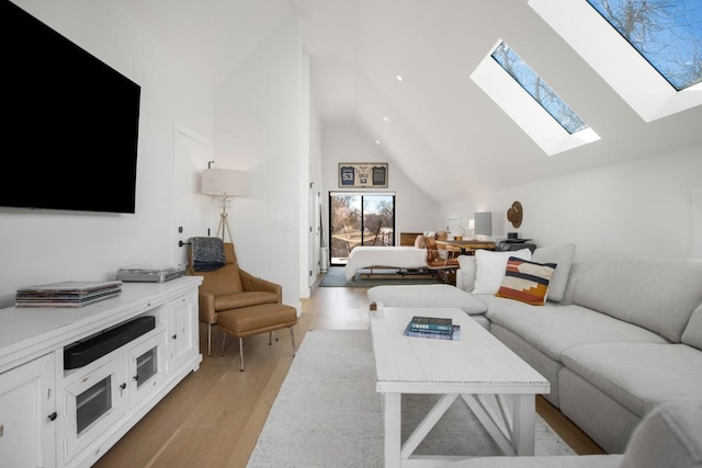 living room featuring light wood finished floors, a skylight, and high vaulted ceiling