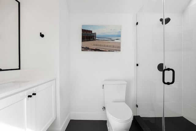 full bathroom with toilet, a shower stall, baseboards, and vanity