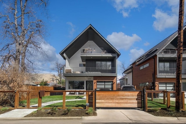 contemporary house with a fenced front yard, a gate, and a balcony