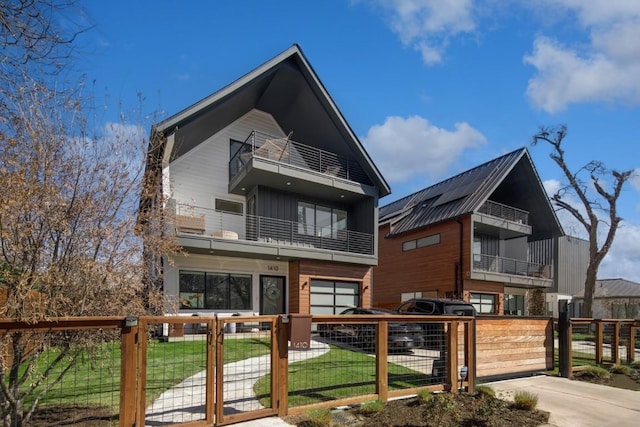 rear view of house featuring a fenced front yard, board and batten siding, a gate, a balcony, and a garage