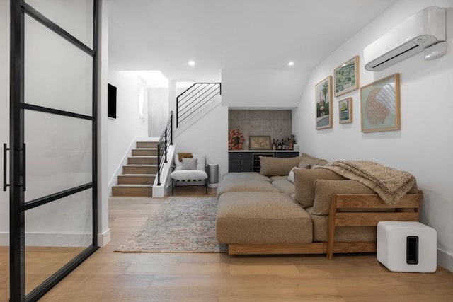 living area with light wood finished floors, stairway, a wall mounted air conditioner, and recessed lighting