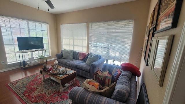 living area featuring wood finished floors, a ceiling fan, and baseboards