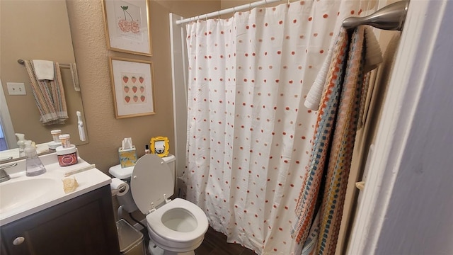 full bath featuring toilet, a shower with curtain, a textured wall, and vanity