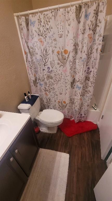 bathroom featuring toilet, a shower with curtain, wood finished floors, and vanity