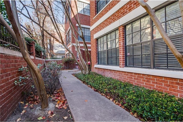 view of property exterior featuring brick siding and fence