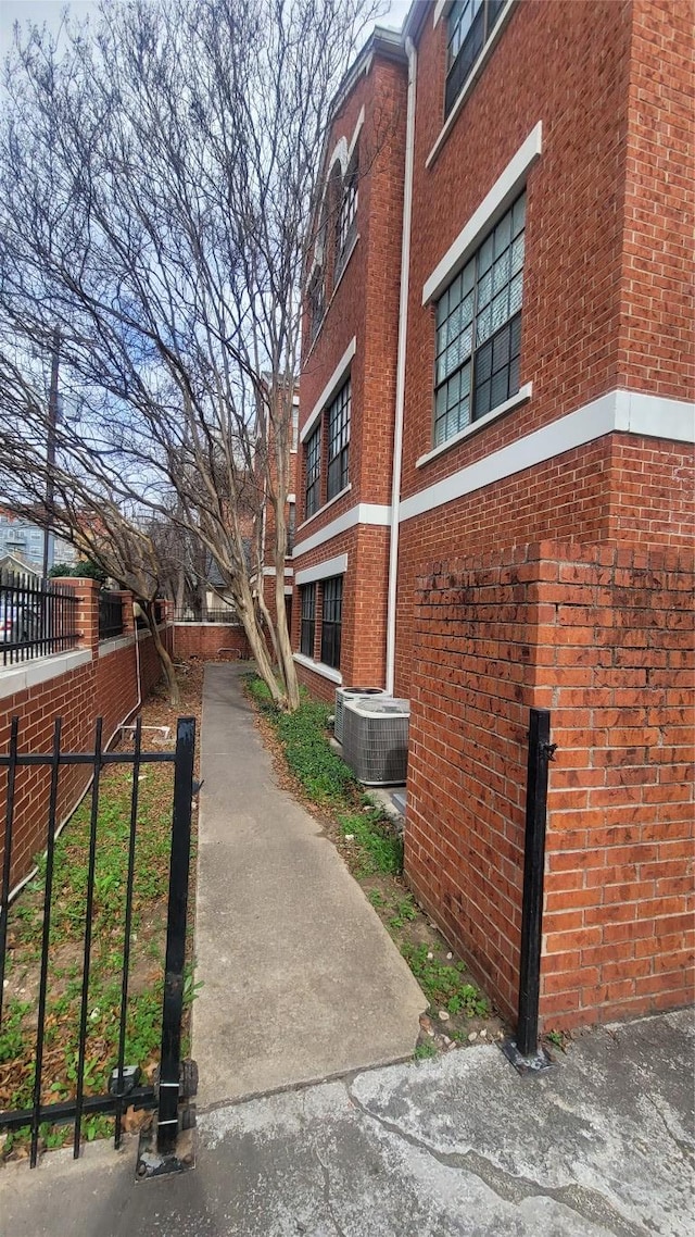 exterior space with brick siding, fence, and central AC