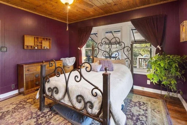 bedroom featuring wooden walls, baseboards, wooden ceiling, wood finished floors, and crown molding