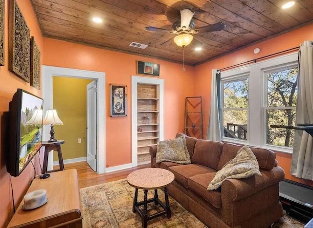 living room featuring wooden ceiling, wood finished floors, visible vents, and a ceiling fan