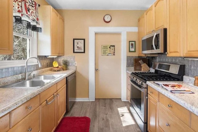 kitchen with tasteful backsplash, light countertops, light brown cabinetry, appliances with stainless steel finishes, and a sink