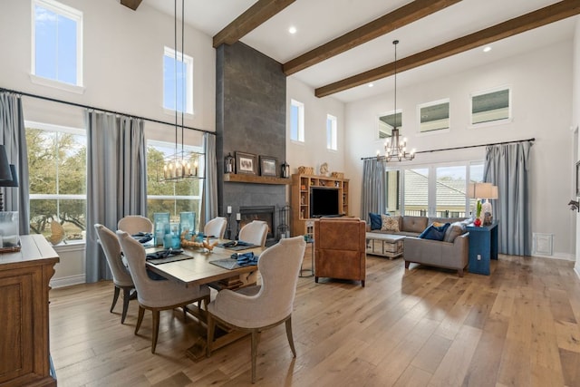 1000 Flint Ridge Trl, Georgetown, TX 78628 - dining space with a chandelier, a high ceiling, a fireplace, light wood-style flooring, and plenty of natural light