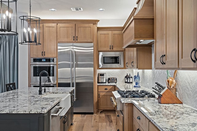 1000 Flint Ridge Trl, Georgetown, TX 78628 - kitchen with built in appliances, premium range hood, light wood-type flooring, light stone countertops, and a sink